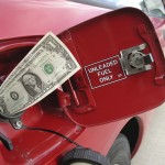 Dollar bill in mouth of gas tank