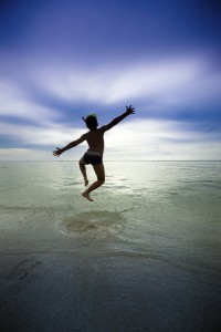 Happy boy jumping by the ocean